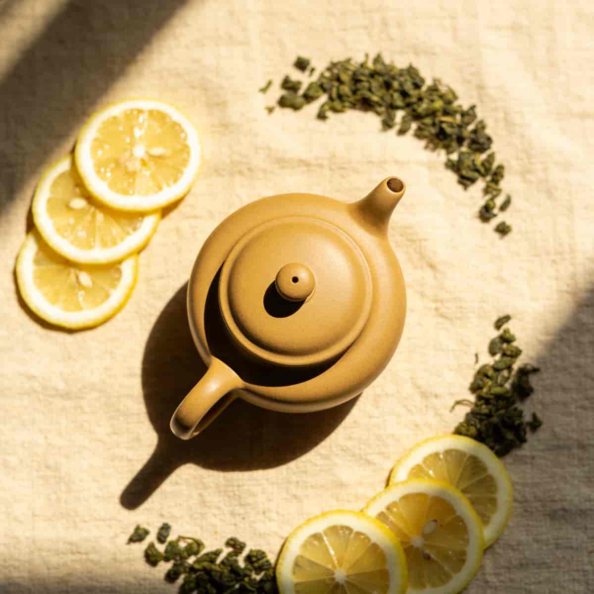 Product photography of a matte ceramic teapot styled on textured linen with soft window light from t