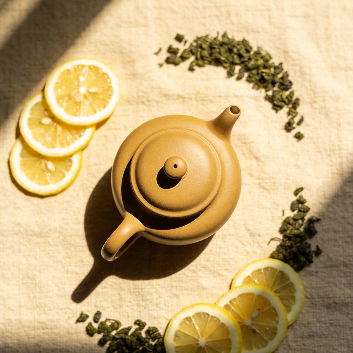 Product photography of a matte ceramic teapot styled on textured linen with soft window light from t